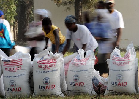 Image of people picking up bags of U.S. rice from food aid shipment