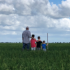 Farmer standing in a rice field with three sons